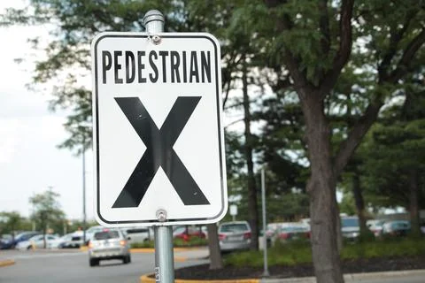 Pedestrian x vertical rectangle white black sign on metal post with parking lot Stock Photos