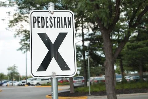 Pedestrian x vertical rectangle white black sign on metal post with parking lot Stock Photos
