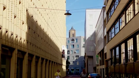 Pedestrians and cyclists navigate narrow city street with historic Eusebius Stock Footage 339837406