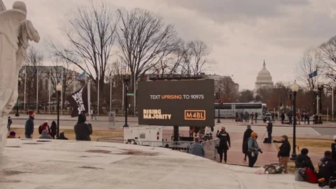 Pedestrians and Protesters Gathering Near George Floyd Display with US Capitol Vidéo 345857553