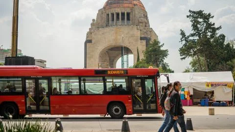 Pedestrians and a Red Bus Passing in Front of the Monument Stock Photos