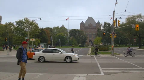 Pedestrians cross intersection infront of Queens Park in Toronto Stock Footage 44266963