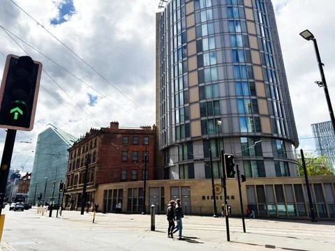 Pedestrians crossing an urban intersection by a modern cylindrical tower Ma.. Stock Photos