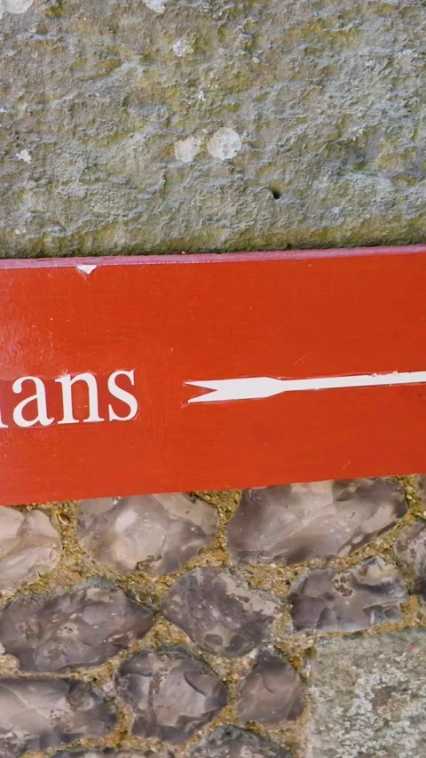 Pedestrians direction sign on stone wall, vertical pan revealing footpath and Vídeo Stock 342295533