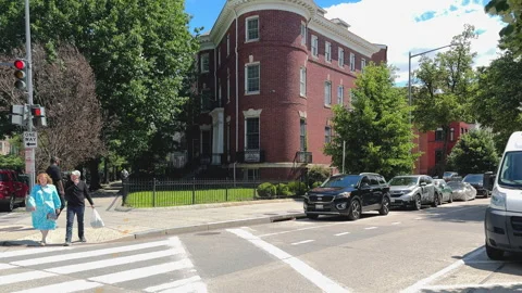Pedestrians wait to cross at red light near historic building Stock Footage 323717791