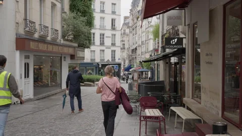 Pedestrians walk down a historic cobblestone pedestrian street past cafes Stock Footage 336722265