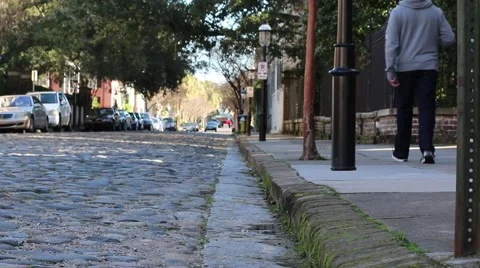 Pedestrians walking curbside next to a cobblestone street in charleston Stock Footage 45631652