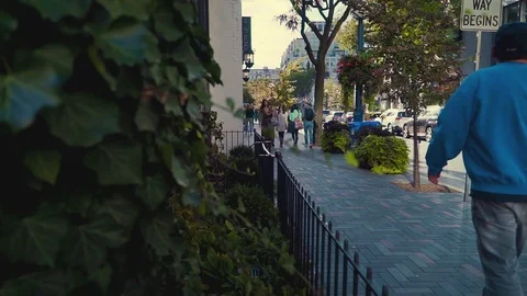 Pedestrians walking down interlocking brick sidewalk in downtown setting Stock Footage 89958880