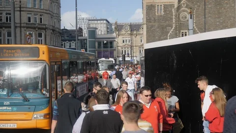 Pedestrians walking down a road to the train station in central cardiff block Stock Footage 114410123