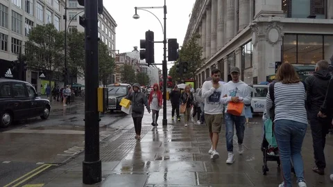 Pedestrians walking in heavy rain on Oxford Street in central London, UK Stock Footage