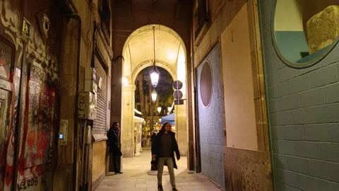 Pedestrians walking through an illuminated ancient passageway in a Barcelona 動画素材 328171174