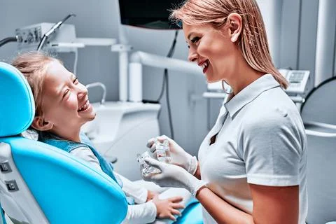 Pediatric dentist educating a smiling little girl about proper tooth-brushing Stock Photos