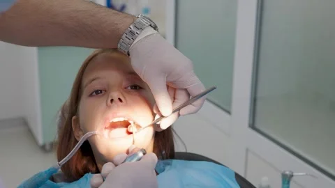 Pediatric dentist examining teeth with mirror for young girl close up. Video stock 340630400