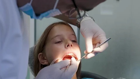 Pediatric dentist examining teeth with mirror and probe for young girl Vidéo 340630613