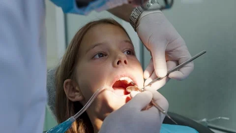 Pediatric dentist examining teeth with mirror and probe for young girl Vídeo Stock 340632821