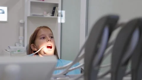 Pediatric dentist inserting saliva ejector for young girl during treatment. Vídeo Stock 340630397