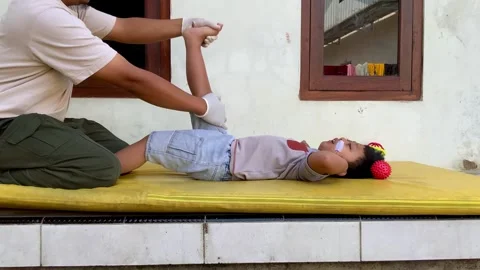Pediatric Physiotherapist Performing Passive Range of Motion Exercise on Child Stock Footage 339394413