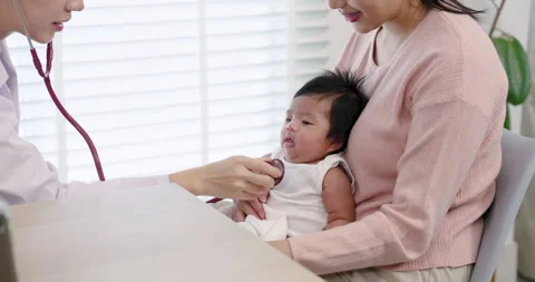 Pediatrician using stethoscope to check newborn baby held by mother during .. Stock Footage 297542367