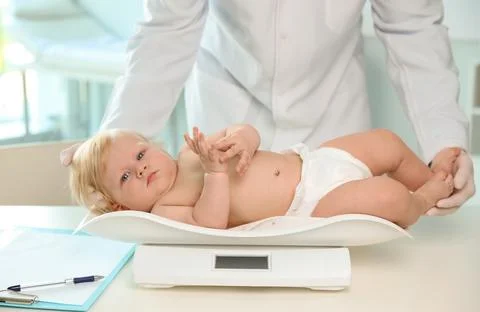 Pediatrician weighting baby on scale in hospital. Healthy growth Stock Photos