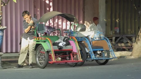 Pedicab drivers sitting and doing activities relaxing while waiting for pas.. Stock Footage 241997558