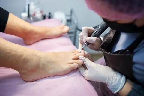 The pedicure master performs the cleaning of the claws of the feet Stock Photos