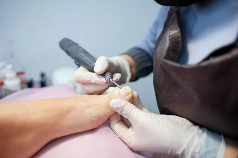 The pedicure master performs the cleaning of the claws of the feet Stock Photos