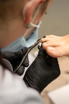 Pedicure master using nail nippers while trimming toenails in a pedicure salon. Stock Photos