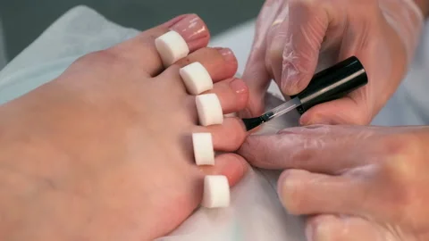 Pedicurist master is applying base coal for shellac on woman's nails on toes. Stock-Footage 163799752