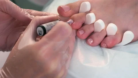 Pedicurist master is applying soft pink gel shellac on woman's toes, closeup. Stock-Footage 168278974