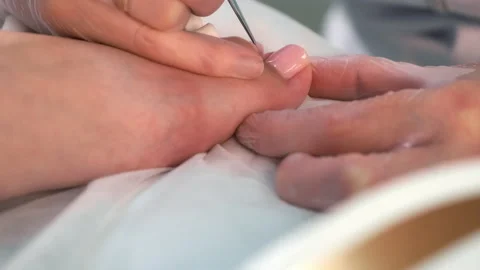 Pedicurist master is applying soft pink gel shellac on woman's toes, closeup. Stock Footage 238086273