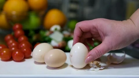 Peel a boiled egg fair skinned woman peeling boiled egg over dish with egg shell Stock Footage 310937680