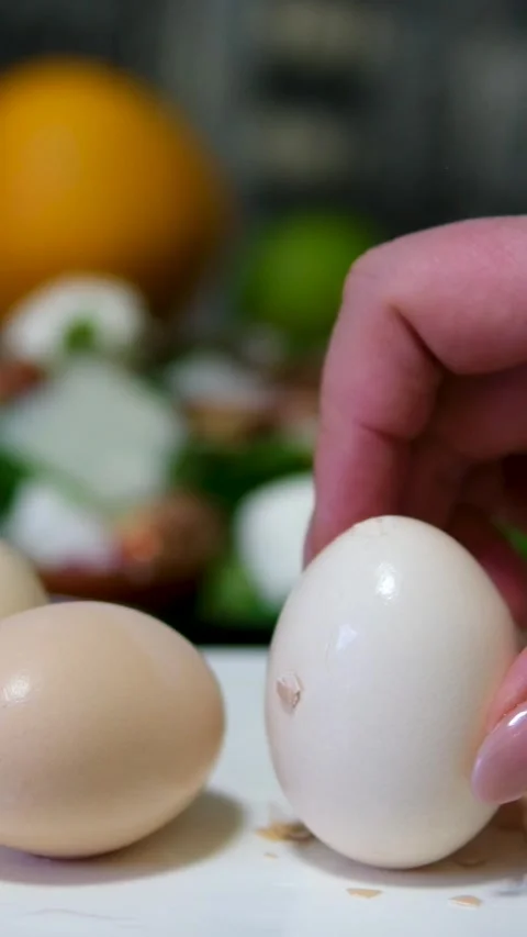 Peel a boiled egg fair skinned woman peeling boiled egg over dish with egg shell Stock Footage 313392602