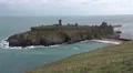 Peel castle with ocean around it, beach visible and many seabirds flying HD Footage