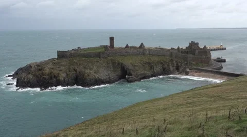 Peel castle with ocean around it, beach visible and many seabirds flying Stock Footage 43179901