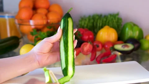 Peel a cucumber Hands using a peeler to remove the skin from a fresh cucumber on Stock Footage 302186819
