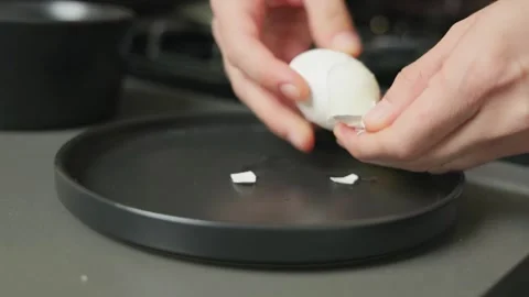 Peel hard boiled eggs in kitchen with black plate Stock Footage 318997999