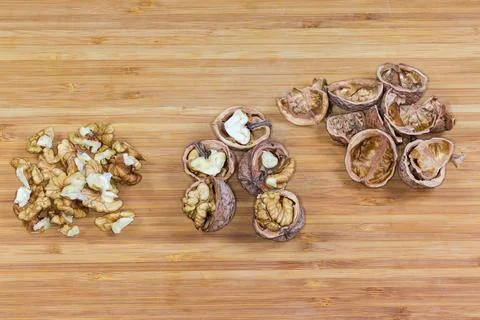 Peeled and split walnuts, their empty shells on wooden surface Stockfoto's