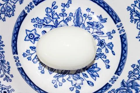 Peeled boiled egg on a plate with patterns. Stock Photos