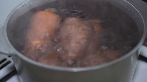 Peeled carrots and potatoes are boiled in a pan with water Stock Footage 128492353
