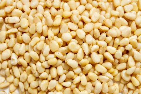 Peeled dried pine nuts as background. Stock Photos