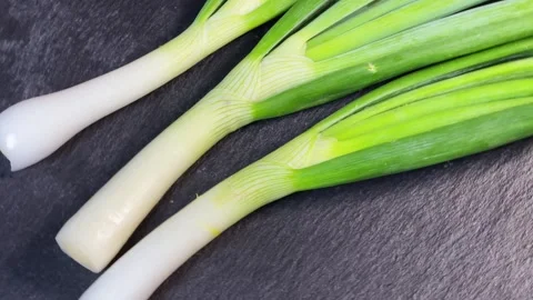 Peeled green onions on a black flat slate serving plate 動画素材 337653351