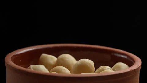 Peeled macadamia nuts fall into the bowl on black background, slow motion Stock Footage 290794195
