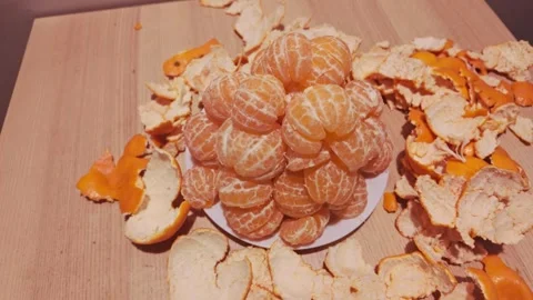 Peeled Mandarin Pyramid on White Plate Surrounded by Fresh Citrus Peels at Home Stock Footage 340258176