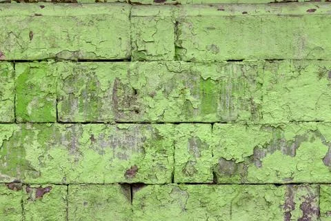 Peeled off old green paint on flat rough brick wall surface - full frame Stock Photos