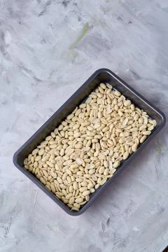 Peeled peanut on baking tray over white textured background, selective focus Stock Photos
