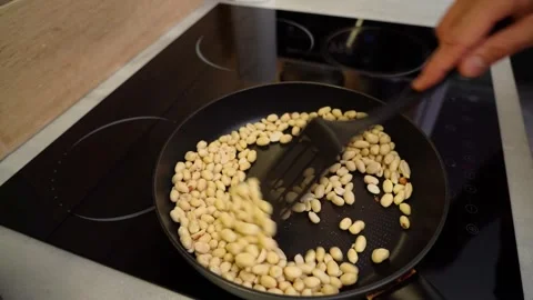 Peeled peanuts are fried in a pan and stirred with a kitchen spatula Stock Footage 249820211