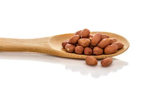 Peeled peanuts. A nut in a spoon. Large size premium quality. Isolated on whi Stock Photos