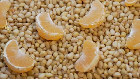 Peeled Pine Nuts and Tangerine Fruit Slices, Closeup, Rotate. The Concept of Hea Stock Footage 142874306
