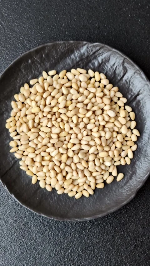 Peeled pine nuts in a bowl on a dark concrete background Stock Footage 305679273