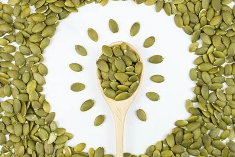 Peeled raw pumpkin seeds lids out in a circle. In the center of the circle is Stock Photos